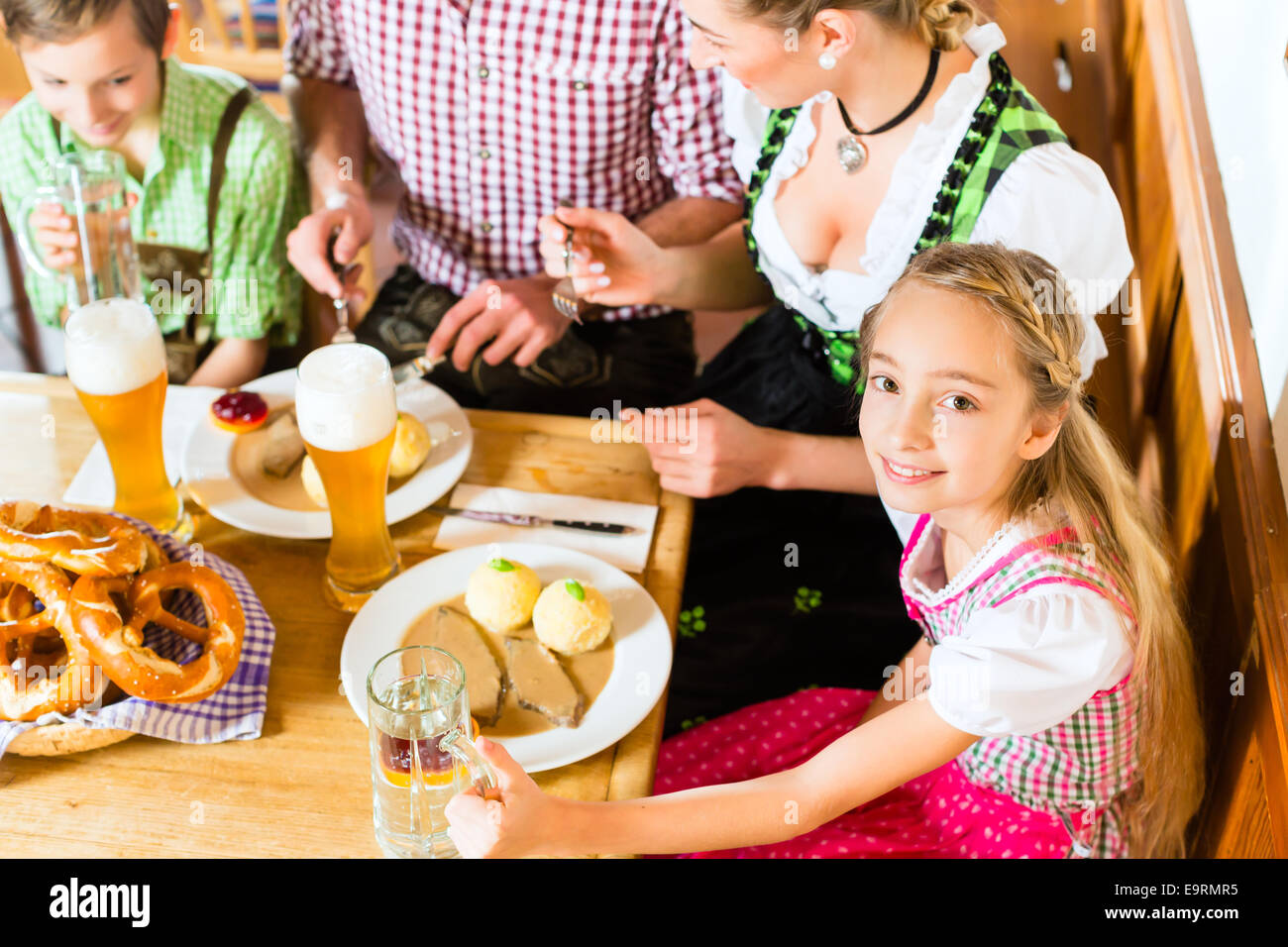 Ragazza bavarese indossando dirndl e mangiare con la famiglia nel ristorante tradizionale Foto Stock