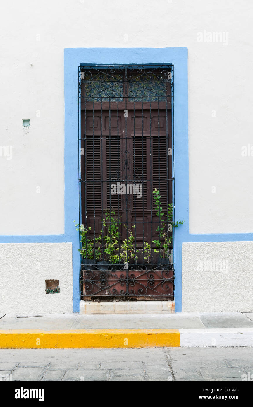 White coloniale spagnolo finestra di casa rifilato in azzurro con persiane e di elementi decorativi in ferro battuto e grill piantatrice, Campeche Foto Stock