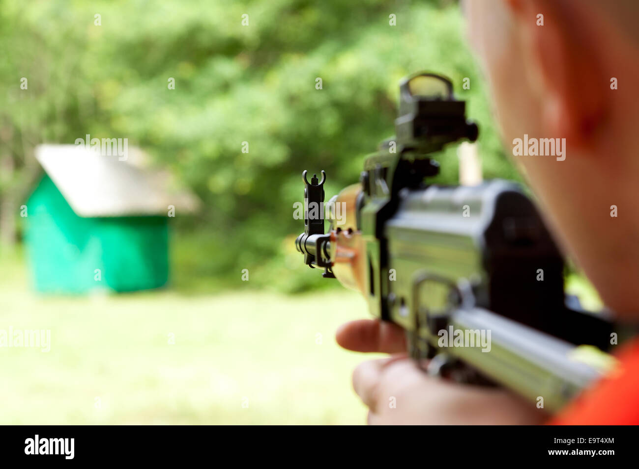 Uomo che ha di mira un bersaglio e la ripresa di un fucile automatico per strikeball. Focus sul fucile attrazioni. Foto Stock