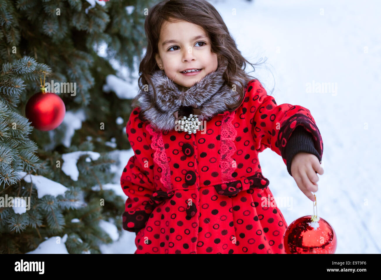 Bambina decorare albero di Natale al di fuori Foto Stock