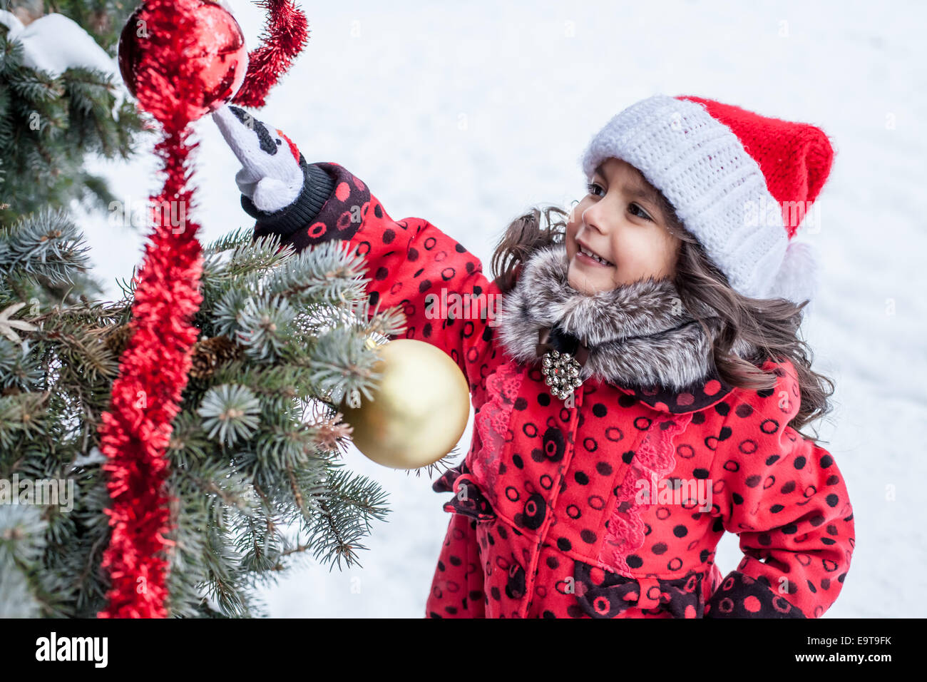 Bambina decorare albero di Natale al di fuori Foto Stock