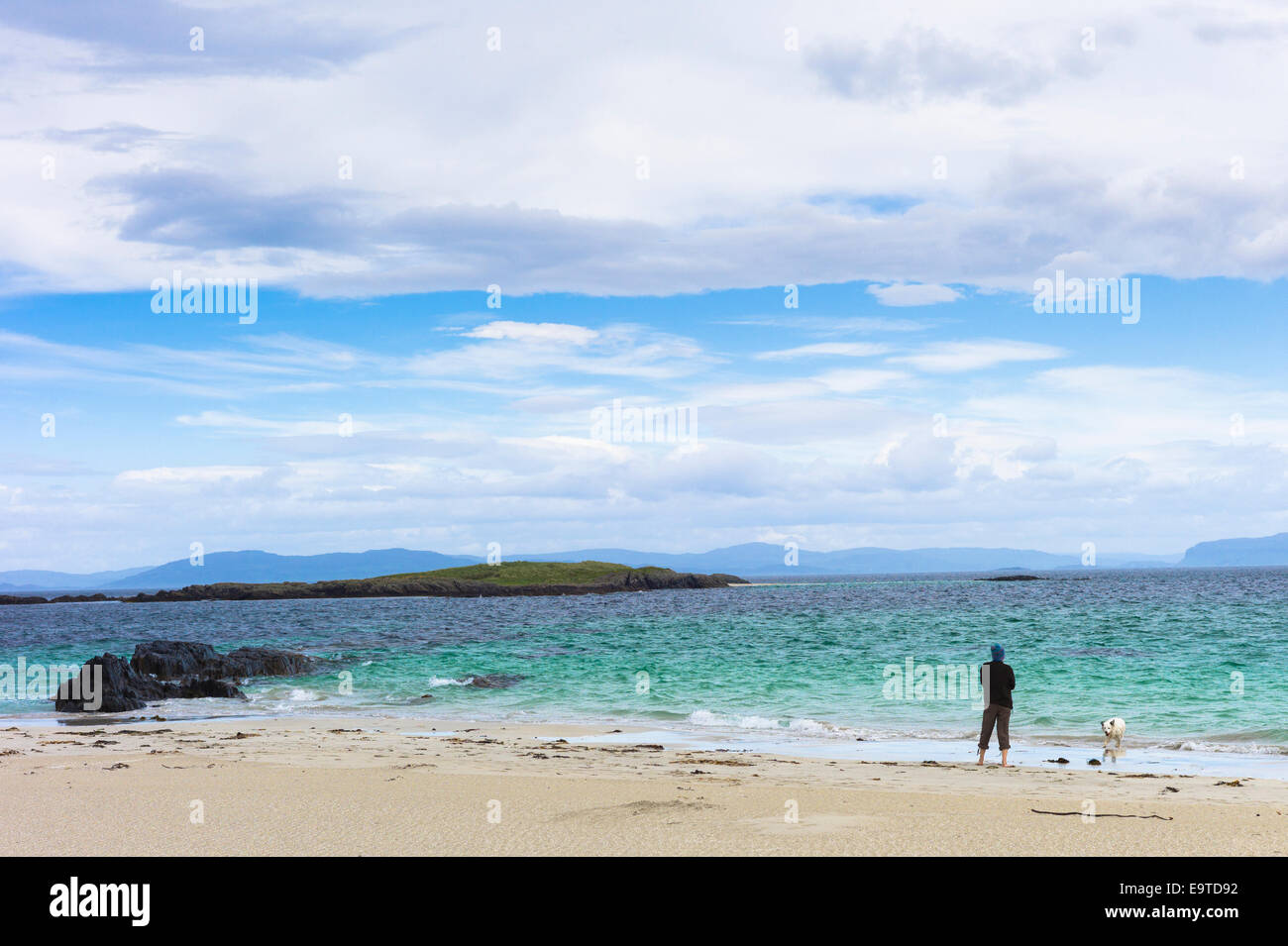 Lone persona con cane sul litorale della spiaggia di sabbia che si affaccia sul mare turchese sull isola di Iona nelle Ebridi Interne e Western Foto Stock