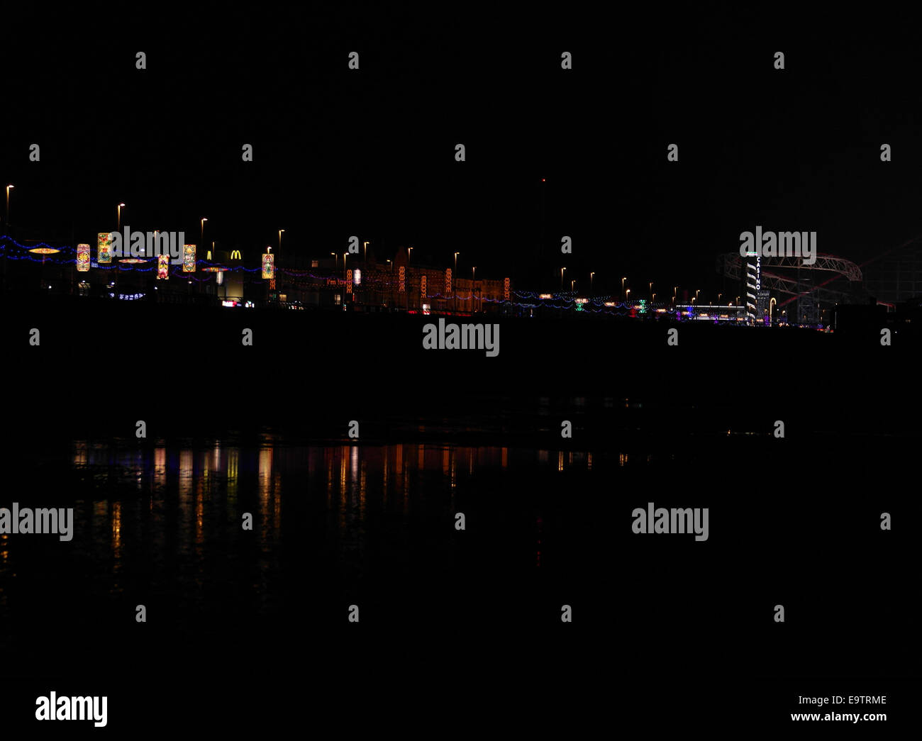 Notte obliqua con vista della spiaggia, con riflessioni, Central Promenade luminarie, a sud verso la Pleasure Beach Casino, Blackpool, Regno Unito Foto Stock