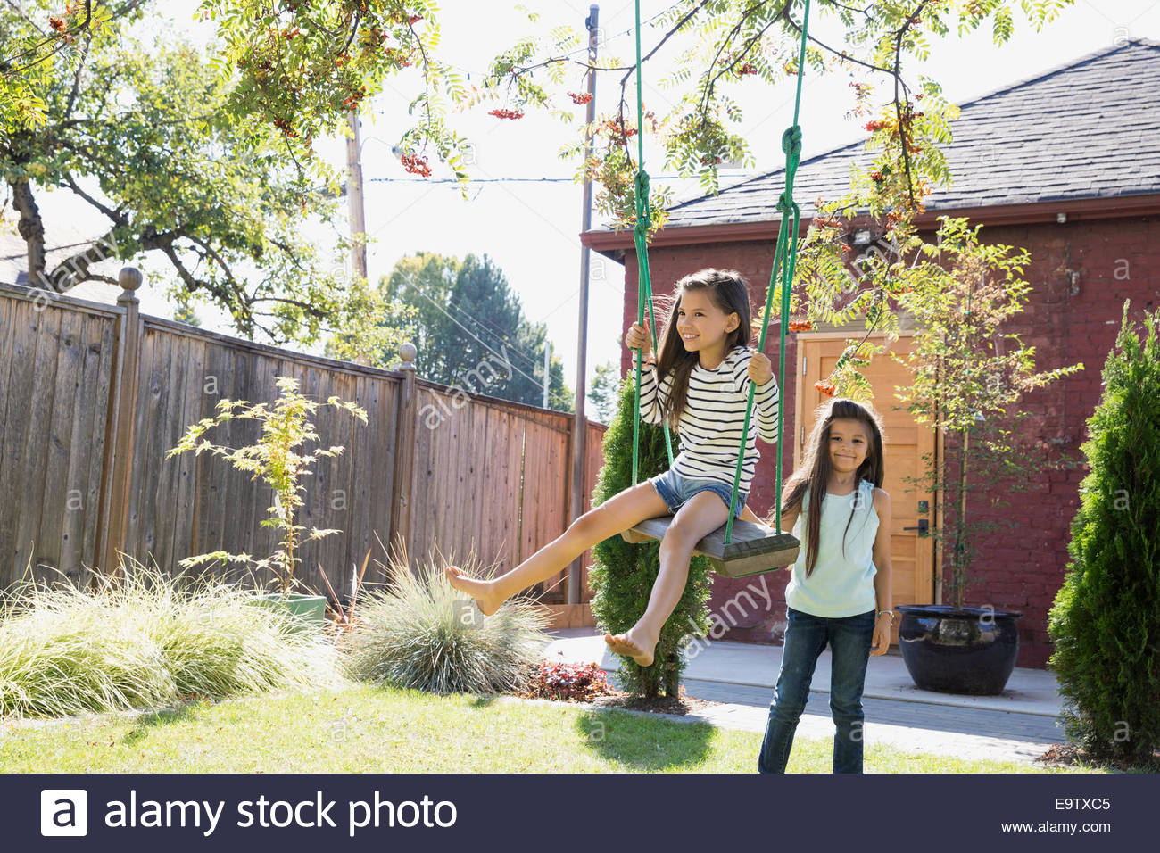 Sorelle giocando su albero oscillante nel cortile posteriore Foto Stock