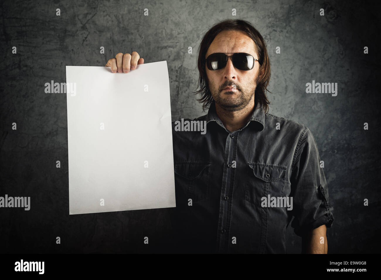 Adulto uomo barbuto in camicia nera tenendo vuoto carta bianca come copia di spazio. Foto Stock