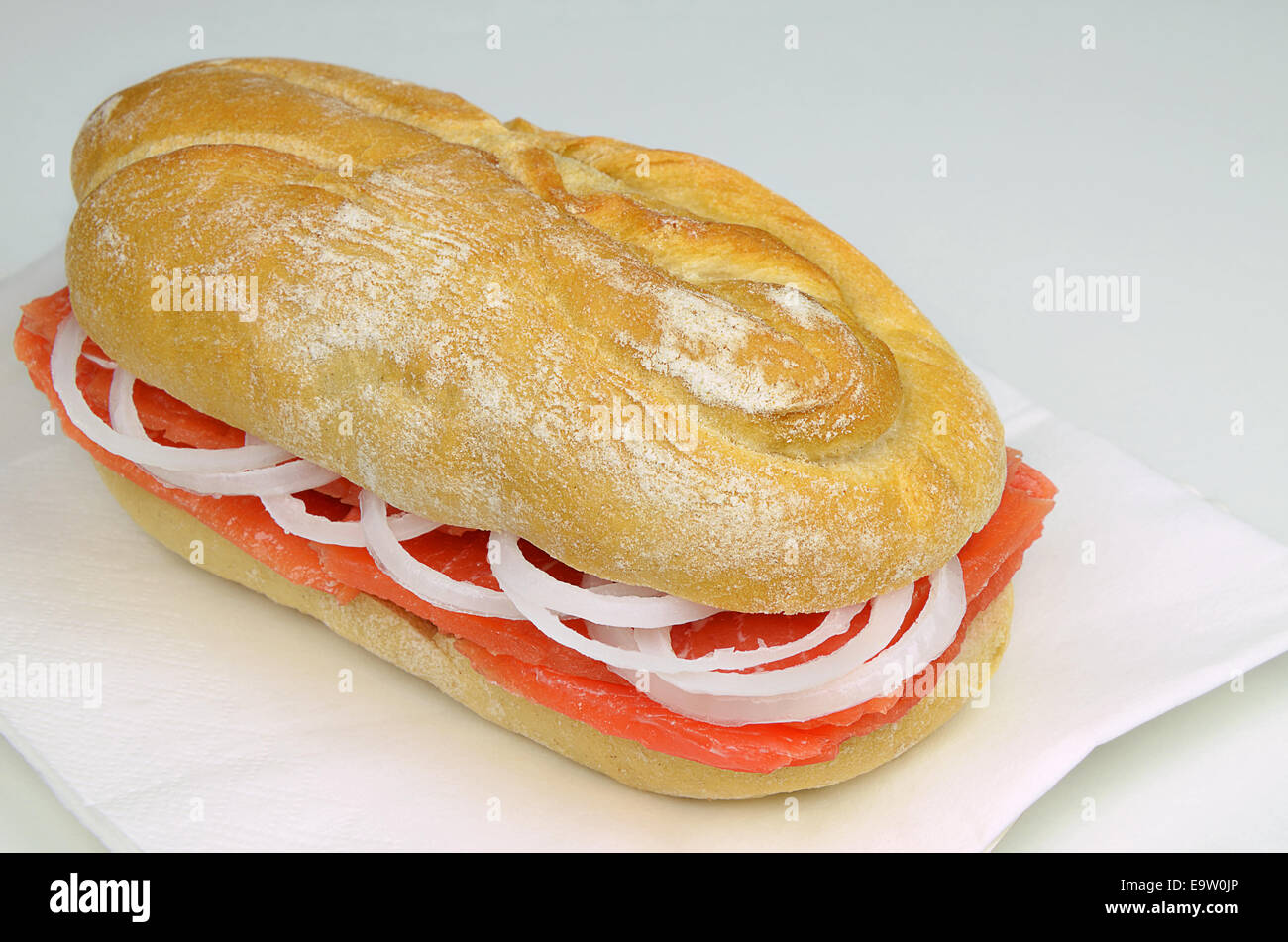 Submarine sandwich con salmone e agli anelli di cipolla sul tovagliolo bianco, close up Foto Stock