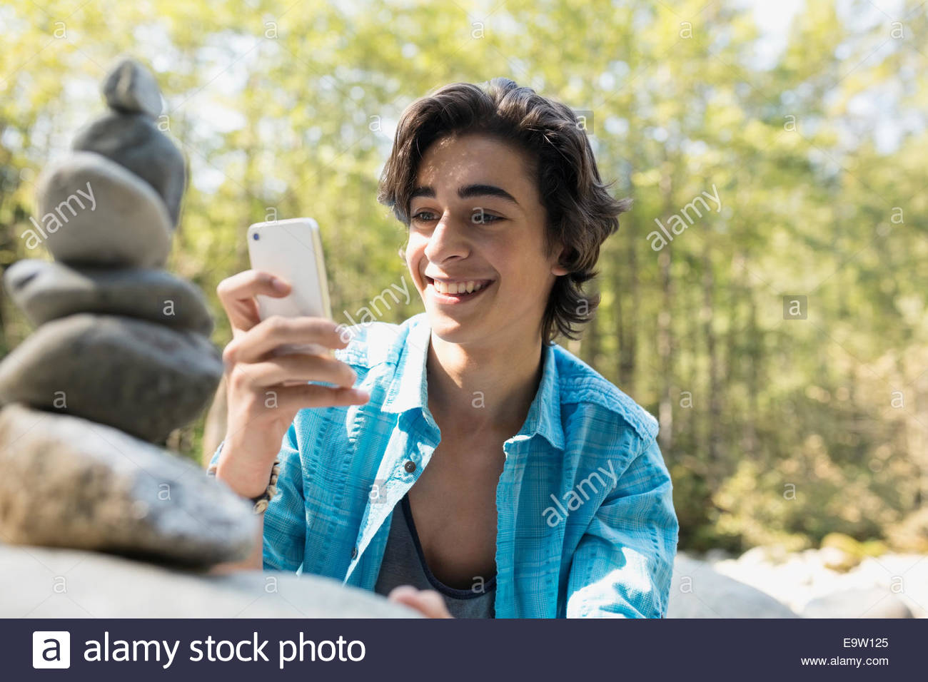 Ragazzo adolescente fotografando pietre impilate nei boschi Foto Stock