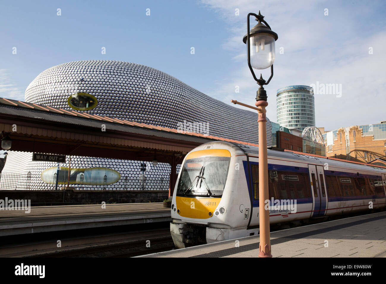 Un Chiltern Railways treno attende presso la piattaforma in Birmingham Moor Street Station, dietro,Selfridges, Rotunda e il Bullring Foto Stock