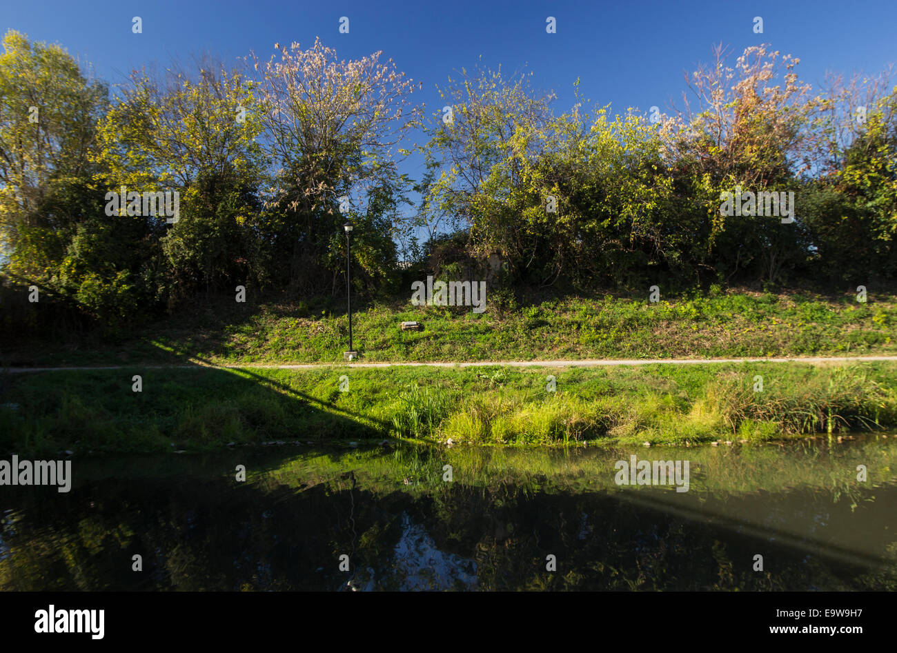 Un passaggio pedonale pavimentato lungo un ruscello che scorre attraverso una greenway. Foto Stock