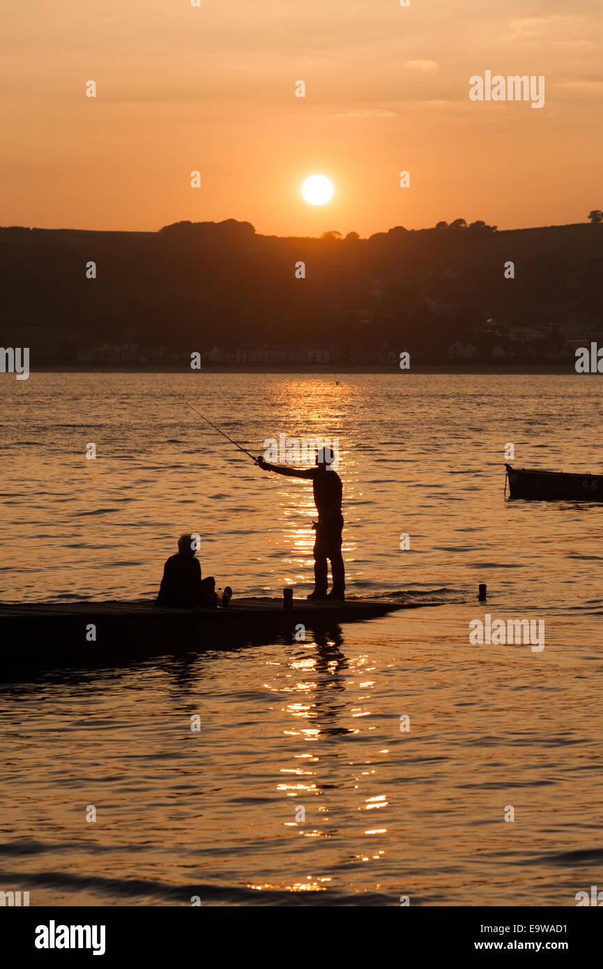 Un uomo stagliano proietta una linea di pesca al tramonto nel fiume Towy, Ferryside, Carmarthenshire, West Wales, Regno Unito Foto Stock
