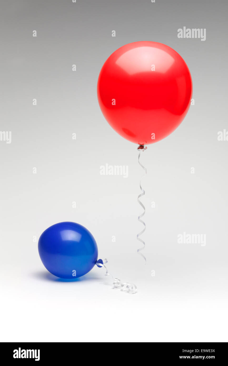 Un rosso palloncino repubblicano che fluttua sopra un parzialmente sgonfio democratica blu palloncino. Foto Stock