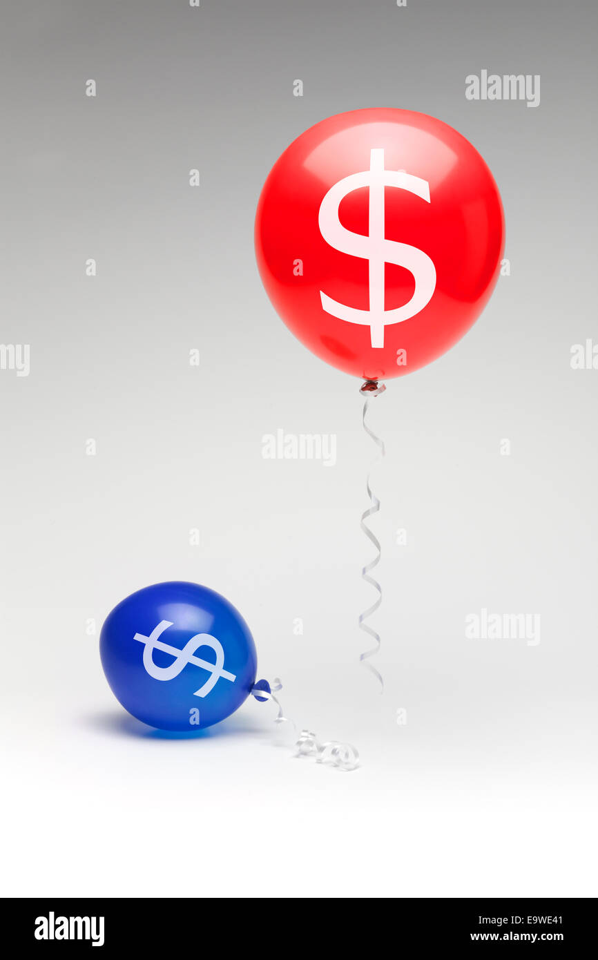 Un rosso palloncino repubblicano che fluttua sopra un parzialmente sgonfio democratica blu palloncino con segni di dollaro. Foto Stock