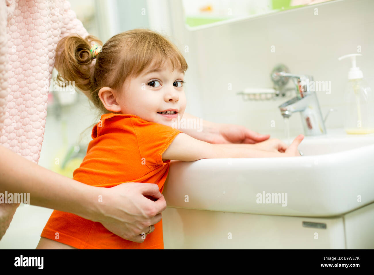 Kid girl lavaggio delle mani con mom help Foto Stock
