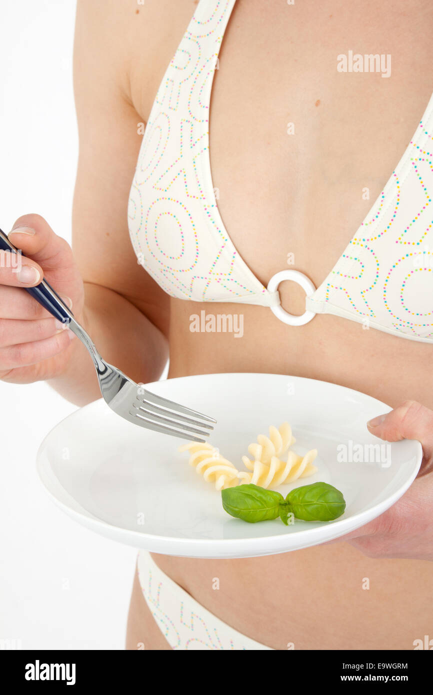 Giovane donna in un bikini di mangiare un piccolo piatto di pasta Foto Stock