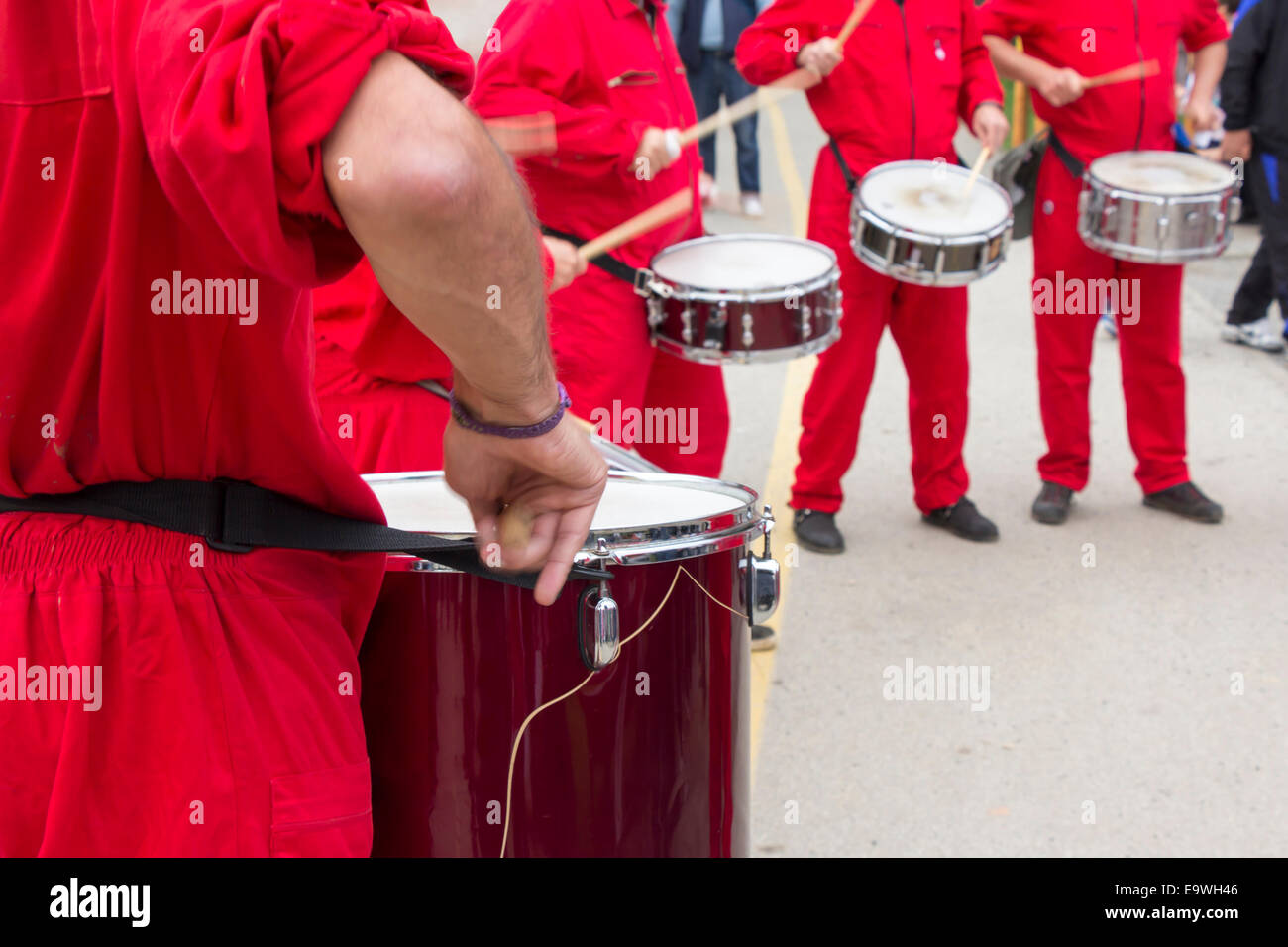 Quattro i percussionisti in tuta rossa drumming per le strade della città Foto Stock