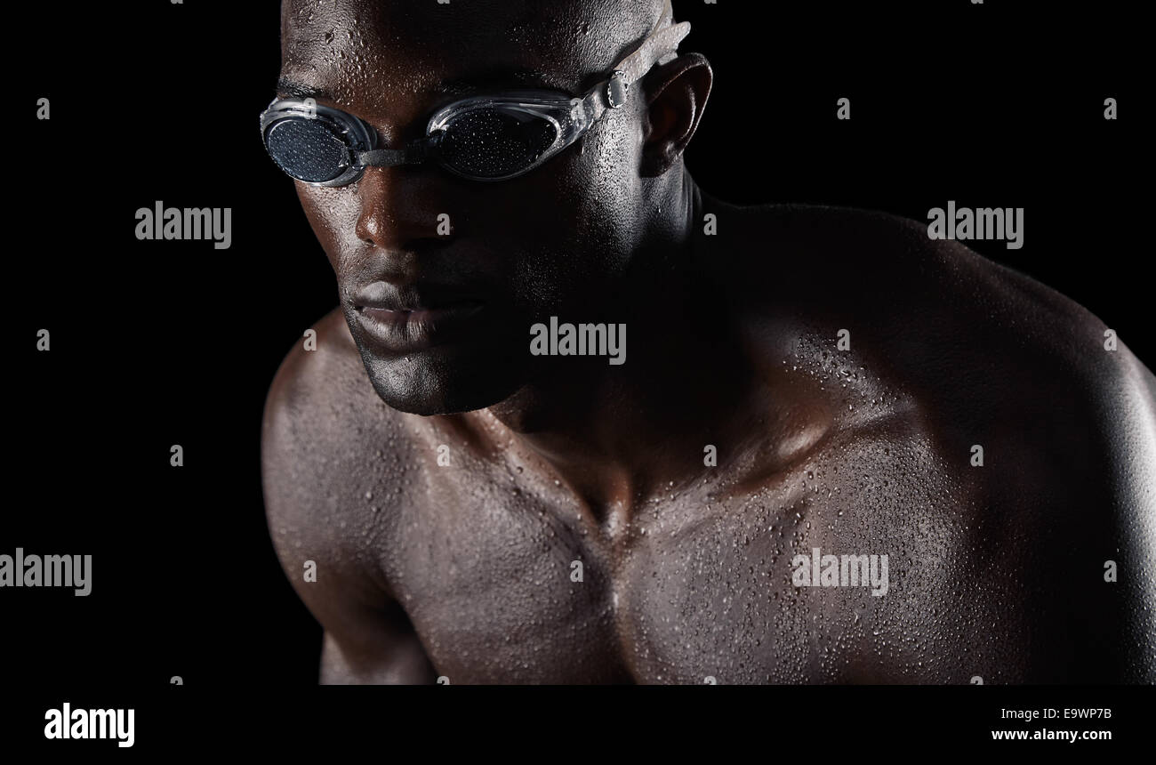 Close-up studio shot del giovane maschio nuotatore allenamento duro per il nuoto la concorrenza. Atleta con corpo muscoloso su nero backgroun Foto Stock