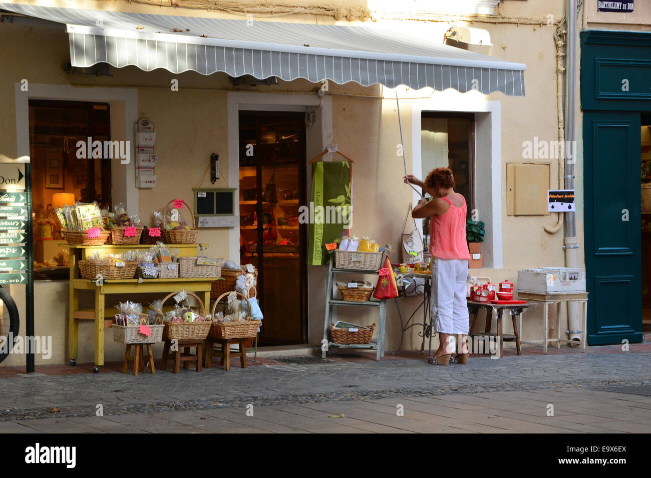 Donna di chiudere il suo negozio di souvenir alla fine della giornata nel sud della Francia Foto Stock
