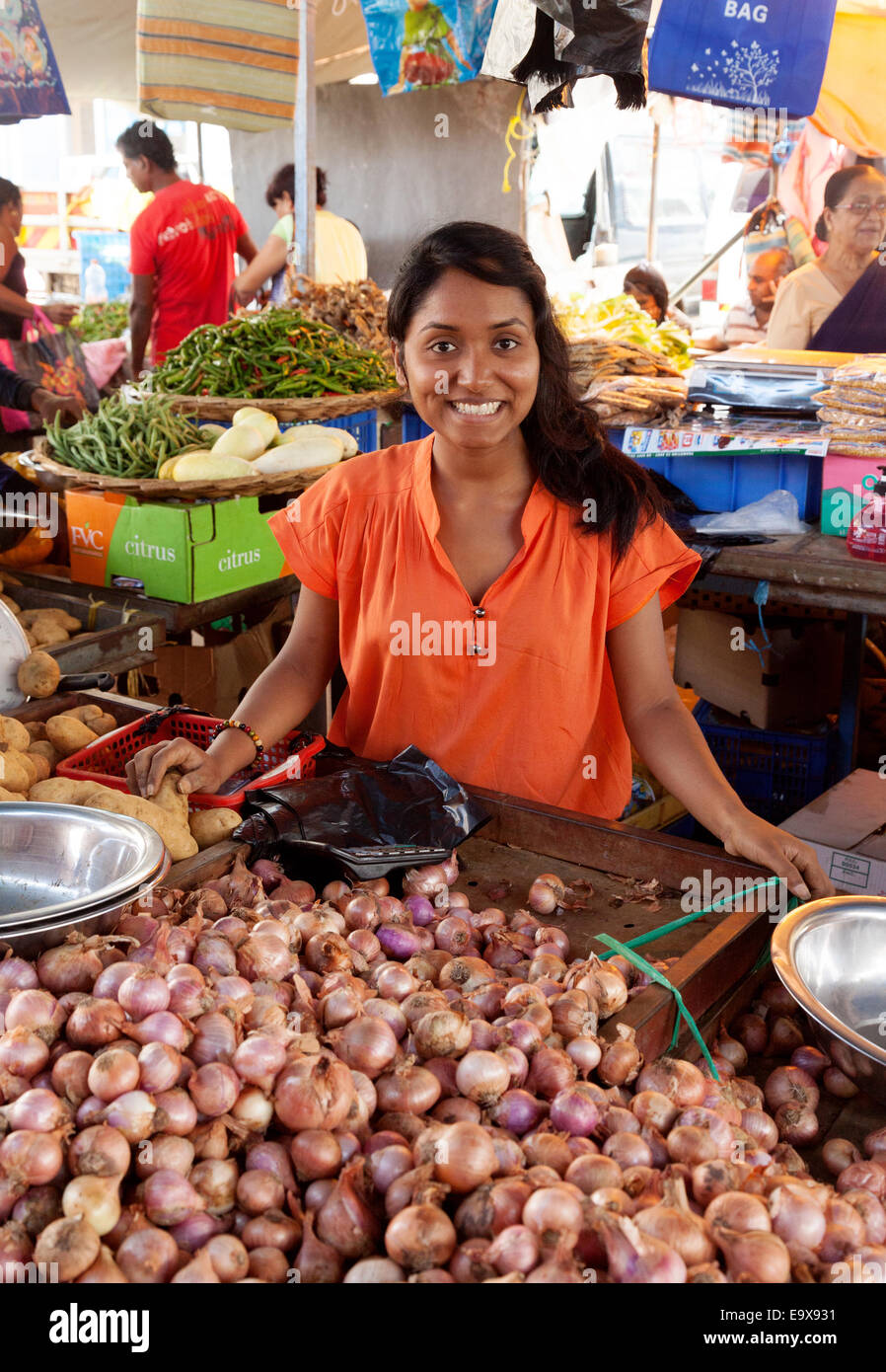 Mauritius Mahebourg; una giovane donna di Maurizio vendita di cipolle al suo stallo, il mercato alimentare di Mahebourg, sud Mauritius Foto Stock