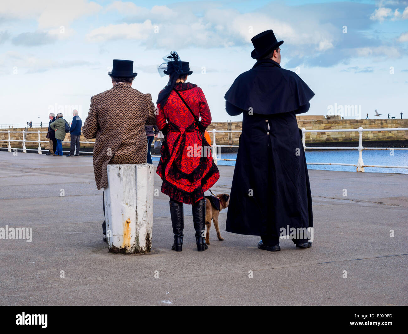 Due uomini una donna e un cane ammirando la vista sul molo Ovest Whitby durante il week-end di Goth Foto Stock