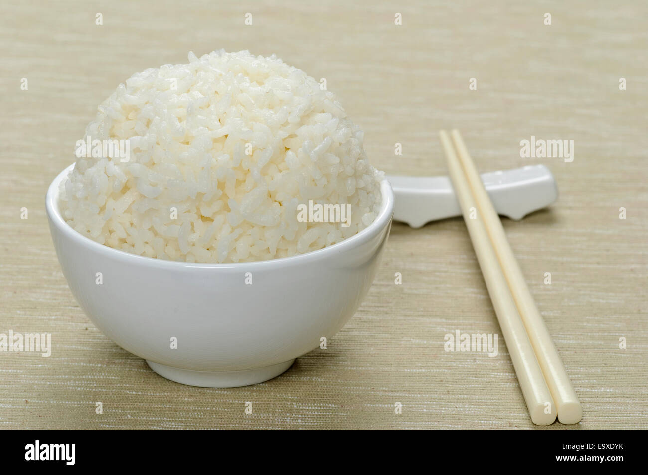 Bianco di riso cotto a vapore nel recipiente di ceramica e bastoncini Foto Stock