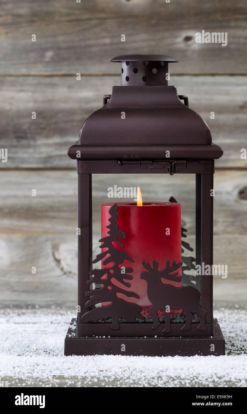 L'immagine verticale della lanterna di vacanza con la masterizzazione di candela rossa all'interno in legno rustico Foto Stock