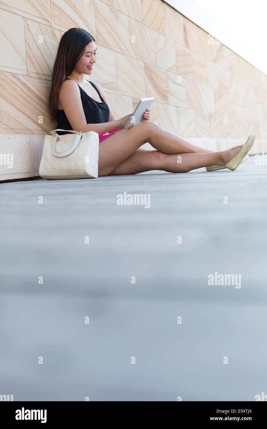 Una giovane donna rilassante mentre guardando i contenuti su un dispositivo tablet pc Foto Stock
