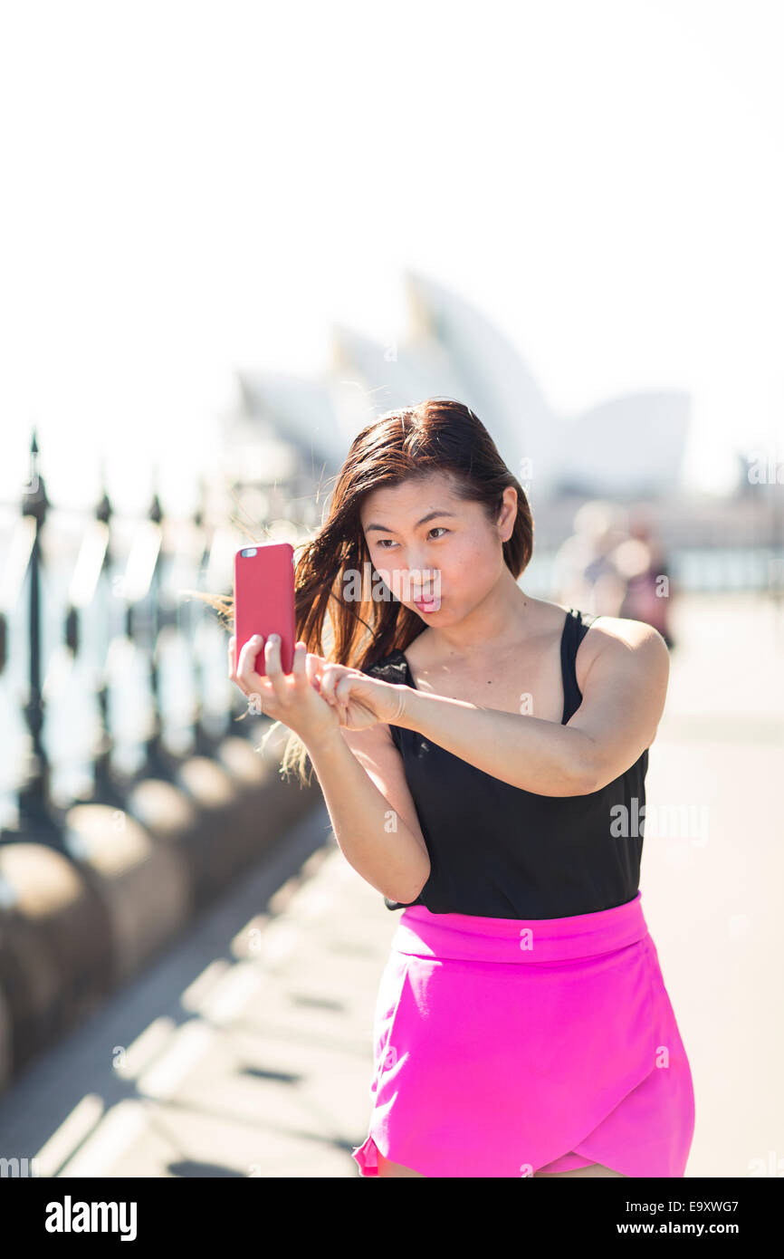 Una giovane donna prendendo un 'selfie' all'aperto tirando una divertente volto Foto Stock