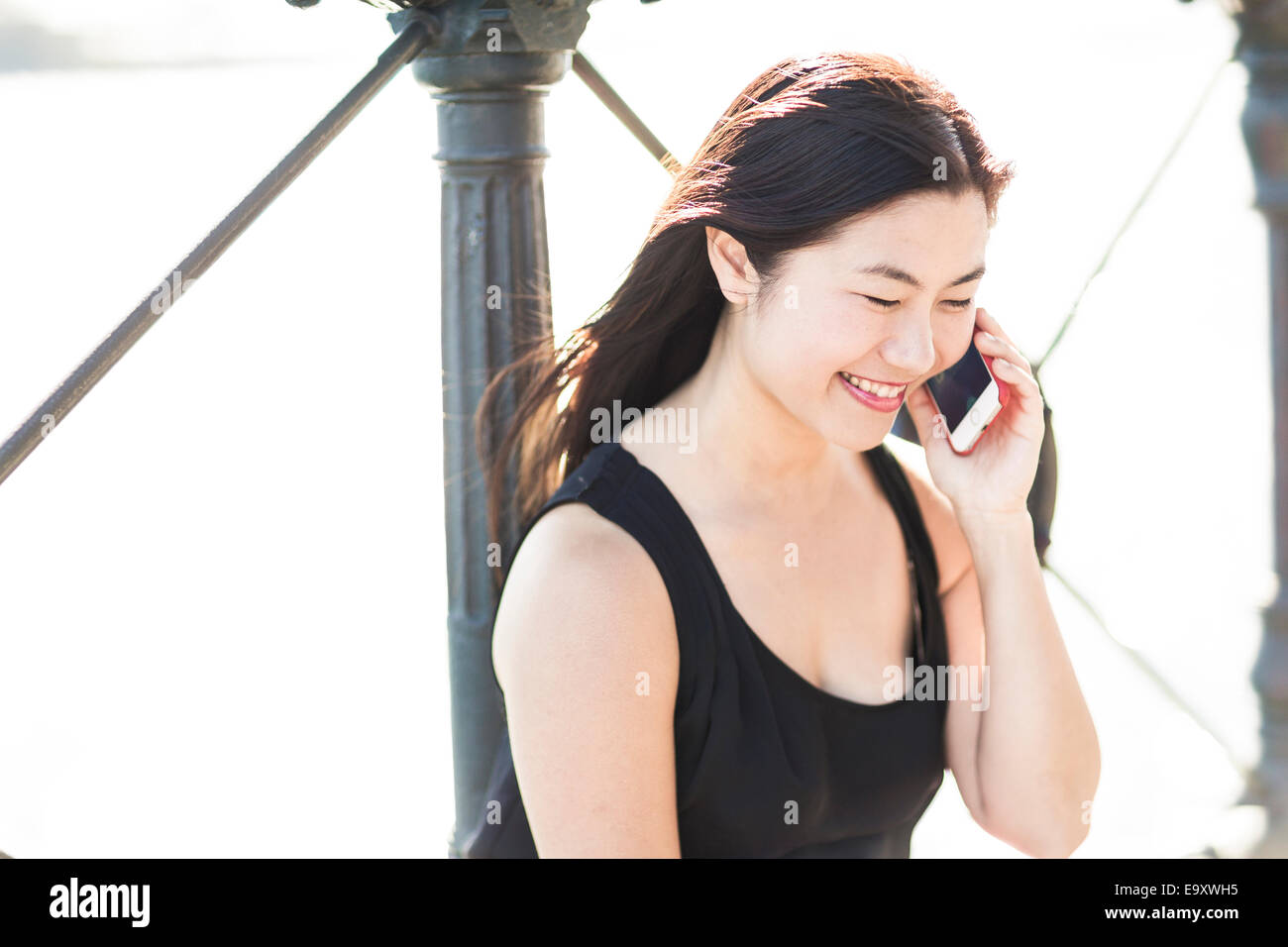 Una giovane donna asiatica parlando su uno smartphone all'aperto Foto Stock
