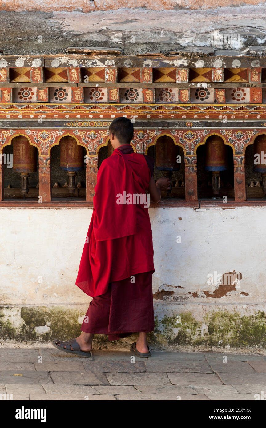 Monaco in piedi nella parte anteriore delle ruote della preghiera a Wangdue Dzong, Wangdue Phodrang, Bhutan Foto Stock