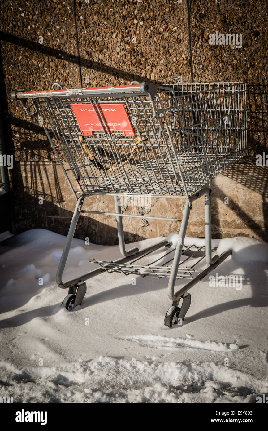 Inutilizzato un carrello seduta nella neve a lato del centro commerciale. Foto Stock