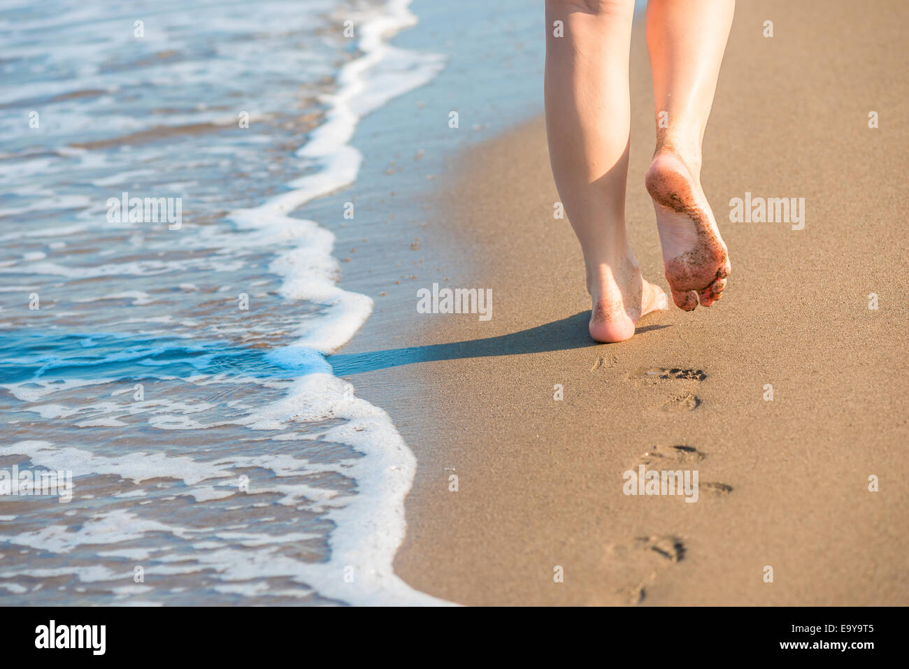 Shapely gambe femmina lasciare impronte su di una spiaggia di sabbia Foto Stock