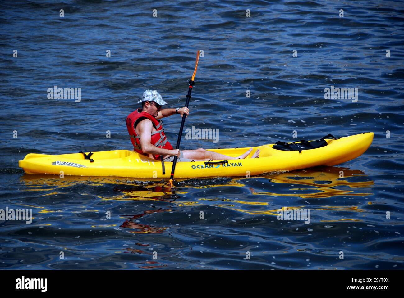 NYC: Uomo paddling suo giallo Kayak lungo le acque del fiume Hudson off Riverside Park Foto Stock