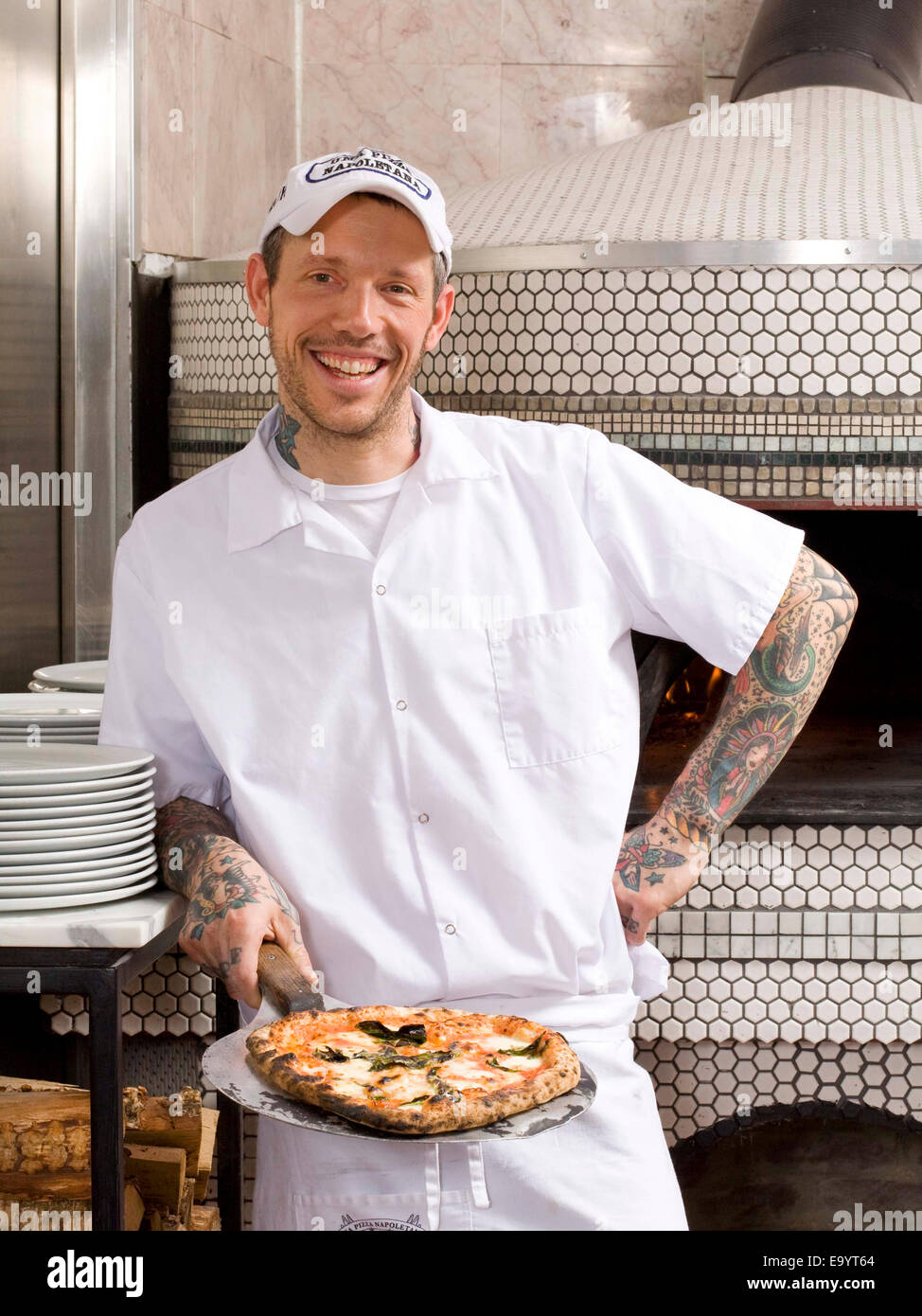 Lo chef con pizza nella parte anteriore del forno per pizze Foto Stock