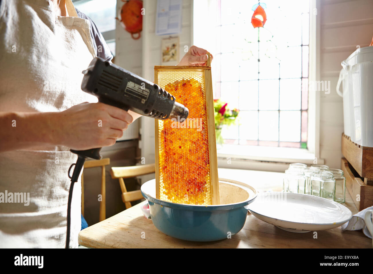 Apicoltore femmina in cucina cera per fusione sul telaio del miele Foto Stock