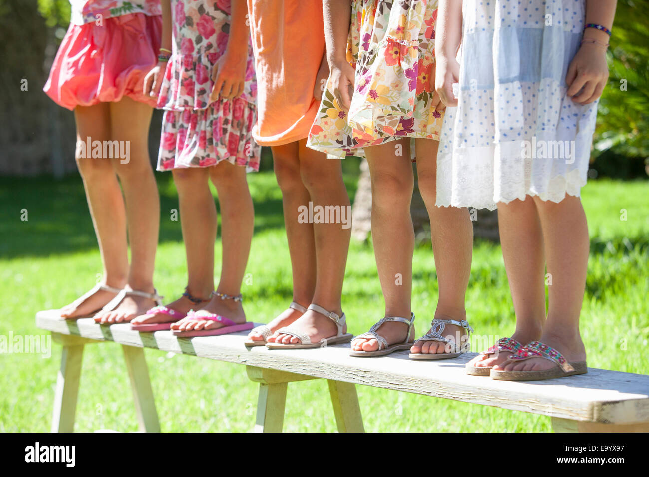Tagliate il colpo di gambe di cinque ragazze permanente sulla panchina da giardino Foto Stock