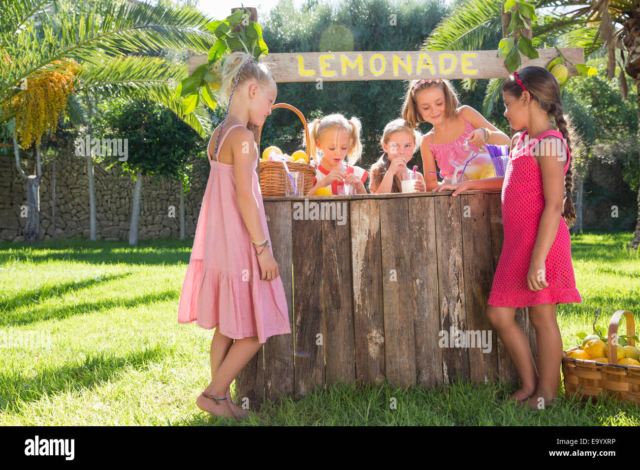 Cinque ragazze versando la limonata e chat a lemonade stand in posizione di parcheggio Foto Stock
