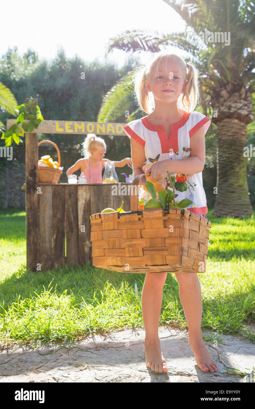 Ritratto di una ragazza che trasportano cesto di limoni nella parte anteriore del piedistallo di limonata Foto Stock
