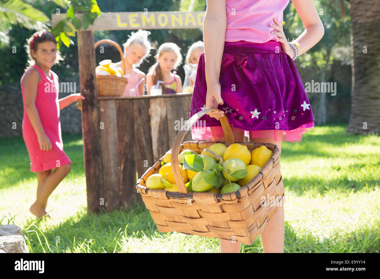 Ritagliato shot della ragazza che trasportano cesto di limoni nella parte anteriore del piedistallo di limonata Foto Stock