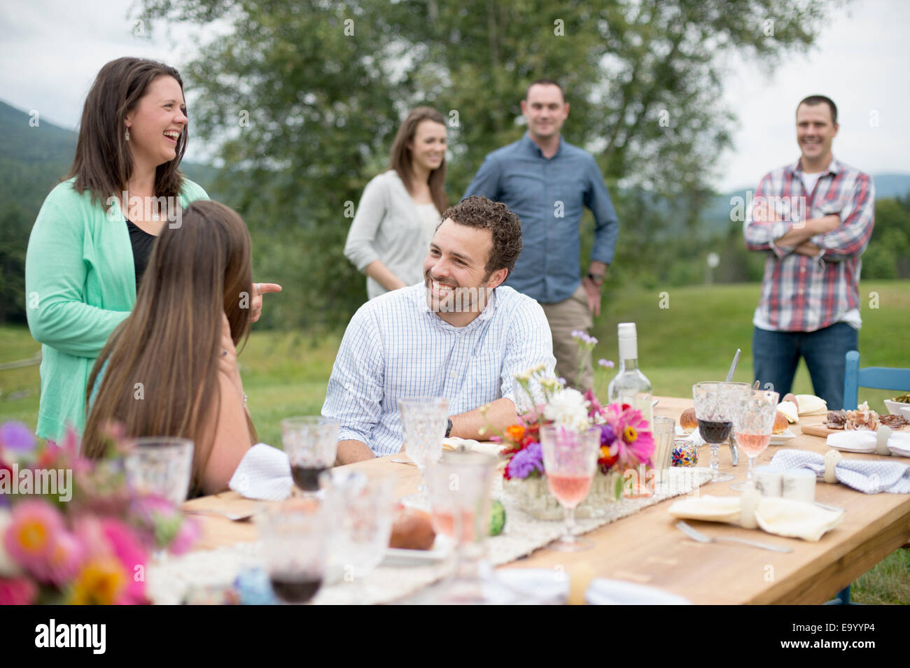 La famiglia e gli amici riuniti intorno, parlare, alla fine di un pasto all'aperto Foto Stock