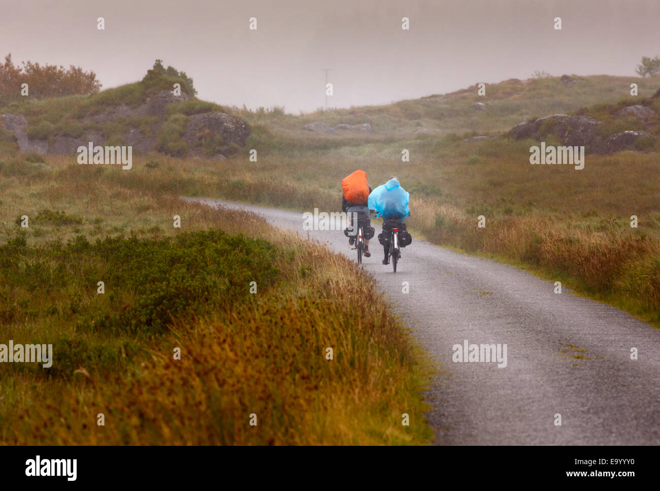 Vicino Derrylea, nella contea di Kerry, Repubblica di Irlanda. Eire. Ecoturismo. Due cicloturisti premere su attraverso la pioggia in una selvaggia Foto Stock