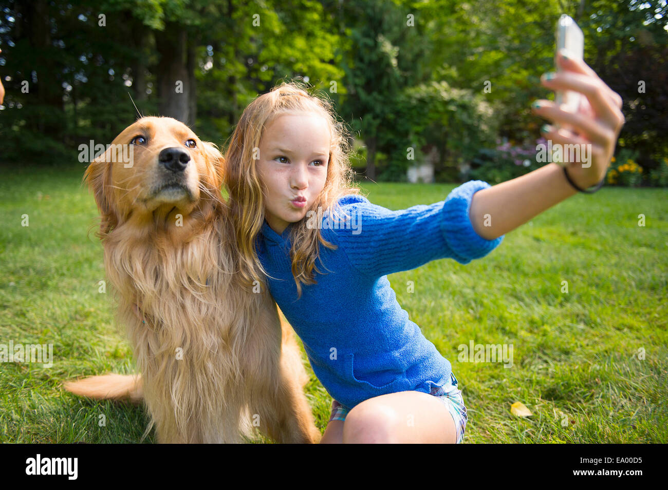 Ragazza tenendo selfie con cane in giardino Foto Stock
