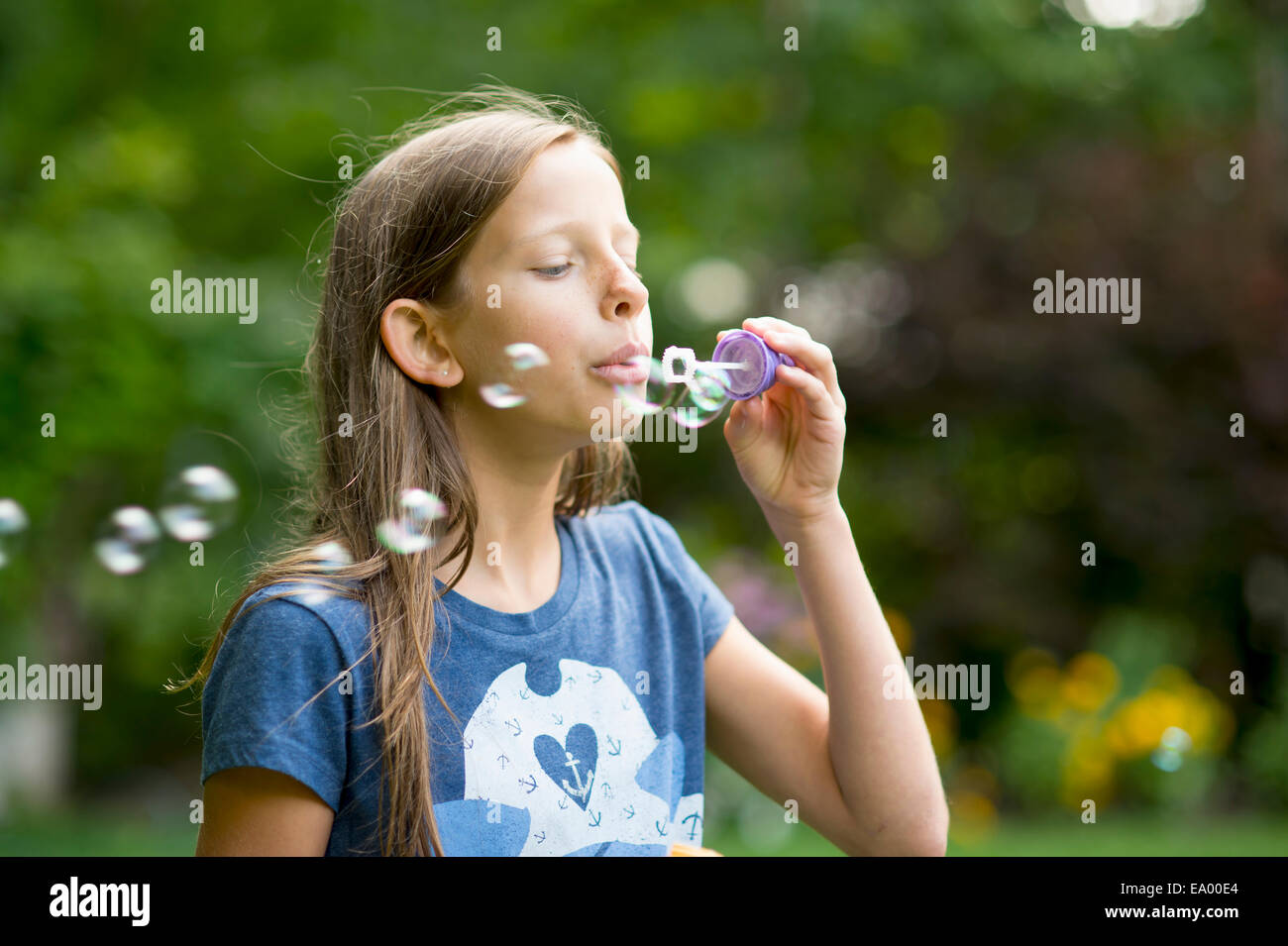 Ragazza a soffiare bolle in giardino Foto Stock