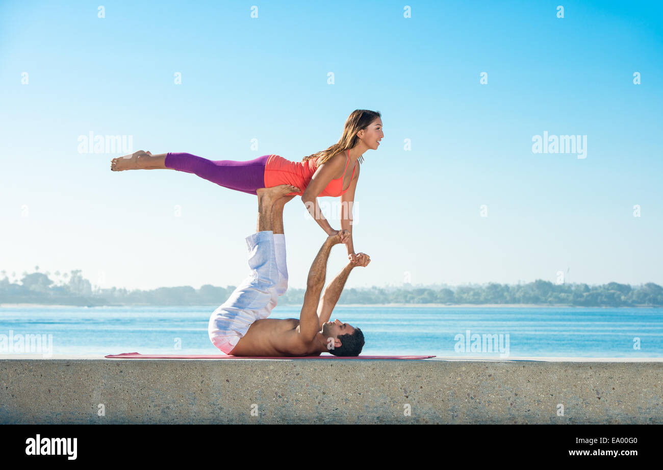 Giovane uomo e donna la pratica dello yoga sul molo a Pacific Beach, San Diego, California, Stati Uniti d'America Foto Stock