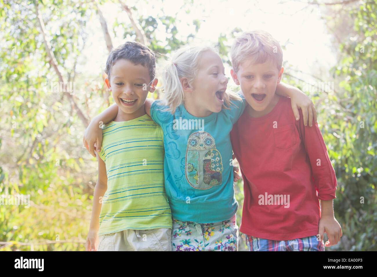 Tre bambini in giardino con le braccia intorno a ciascun altro Foto Stock