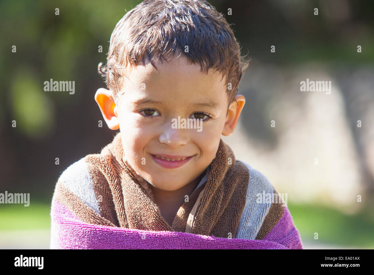 Ritratto di ragazzo con i capelli umidi avvolti nel telo in giardino Foto Stock