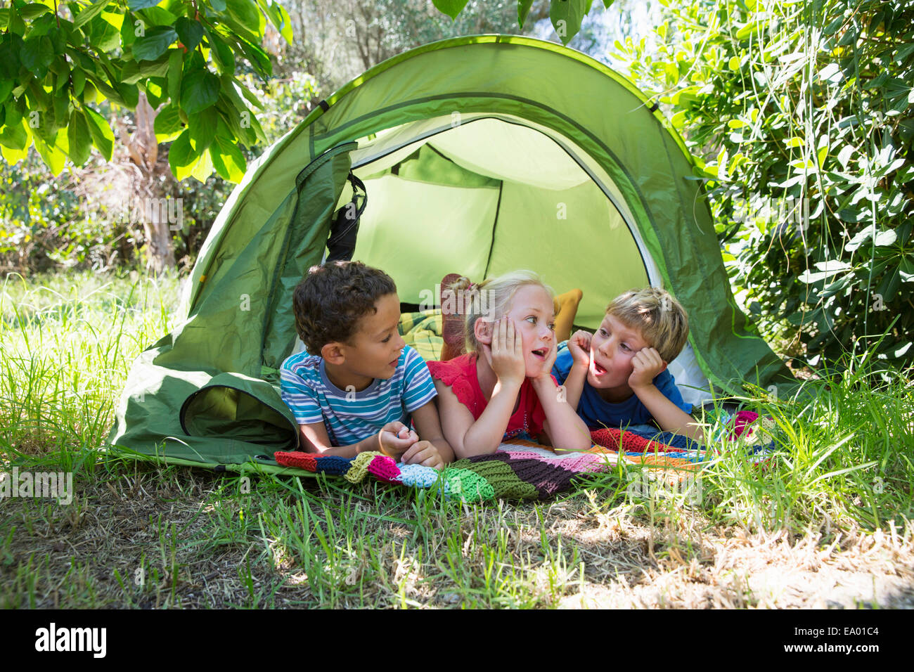 Tre bambini in chat con tenda da giardino Foto Stock