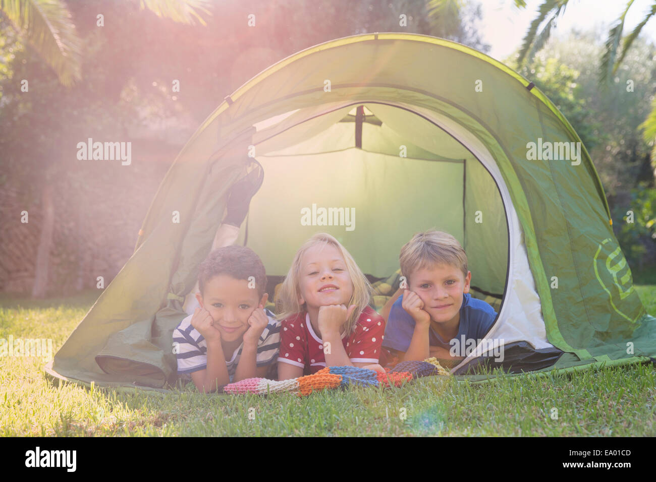 Ritratto di tre bambini che giace nella tenda da giardino Foto Stock