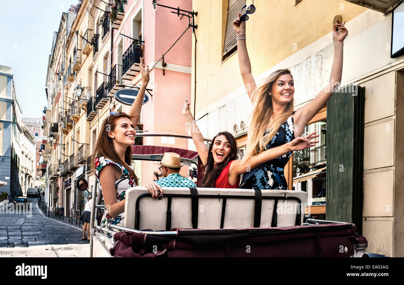 Tre giovani donne in aprire il sedile posteriore di un taxi italiano, Cagliari, Sardegna, Italia Foto Stock