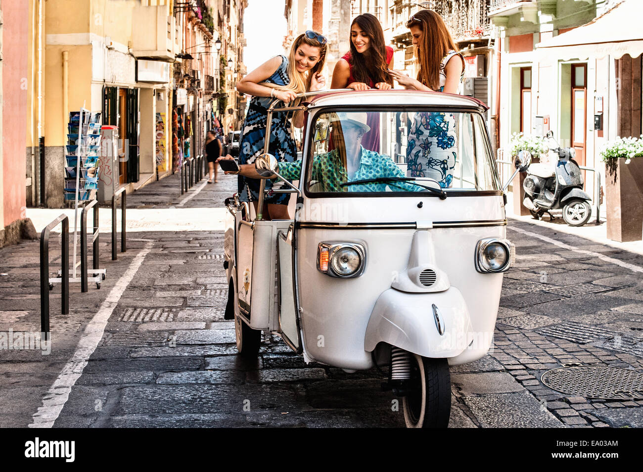 Tre giovani donne in piedi in aprire il sedile posteriore di un taxi italiano, Cagliari, Sardegna, Italia Foto Stock