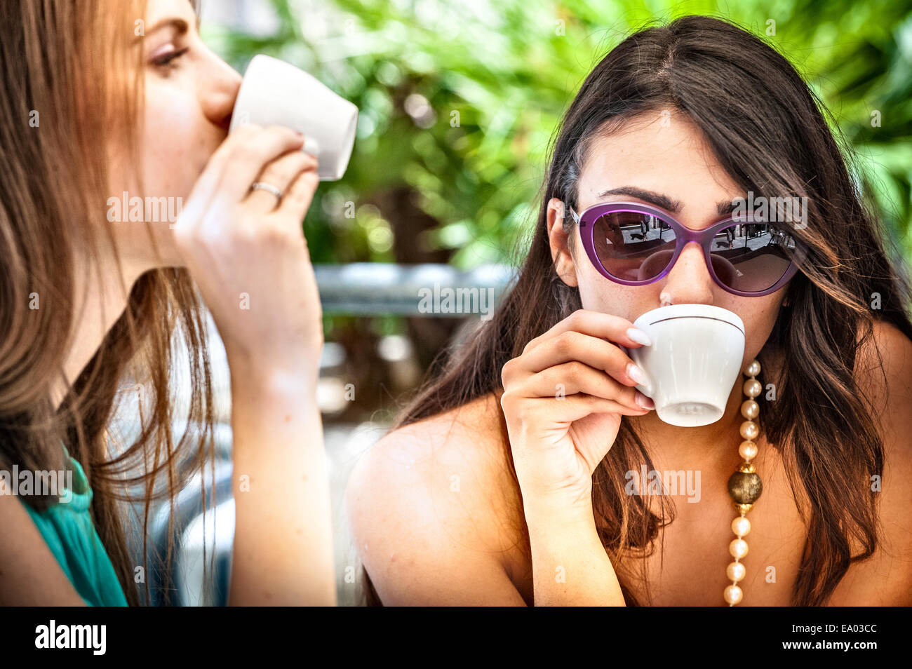 In prossimità dei due giovani amici di sesso femminile di bere espresso al cafè sul marciapiede, Cagliari, Sardegna, Italia Foto Stock
